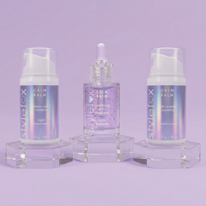 Three skincare products on a white platform with a purple background