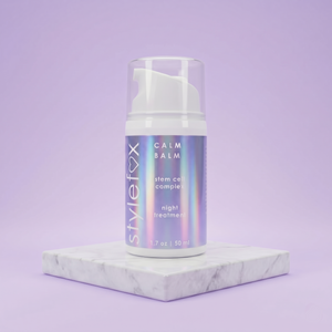 Skincare bottle labeled 'Calm Balm' on a marble platform with a purple background